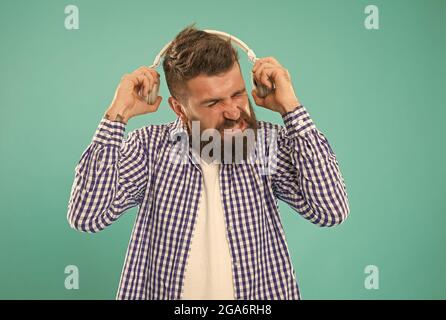kaukasischer Typ mit Bart und Schnurrbart mag keine laute Musik in digitalen Kopfhörern Stockfoto