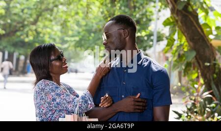 Junge Frau, die im Freien steht und nach dem Einkaufen lächelnd ihren Freund streichelt. Stockfoto