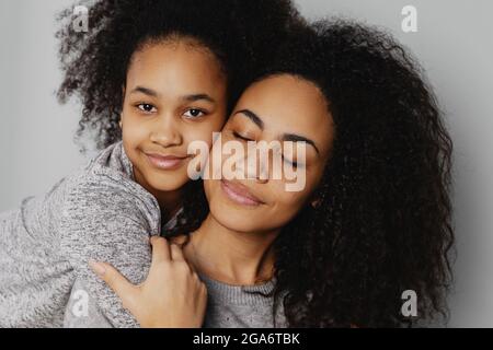 Portrait eines jungen Mädchens, das Mutter von hinten umarmt. Stockfoto