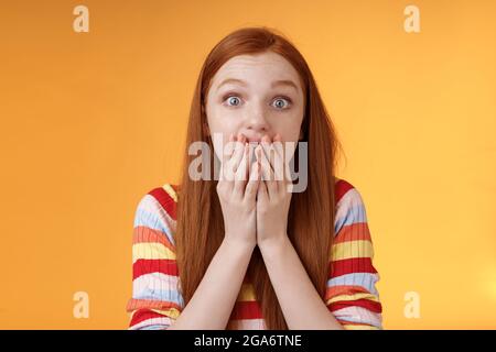 Aufgeregt schockiert Rotschopf sprachlos Mädchen wie Klatsch stehen emotional erstaunt Hören Sie amüsante Geschichte keuchend voller Unglauben decken Mund Handfläche erstaunt Stockfoto