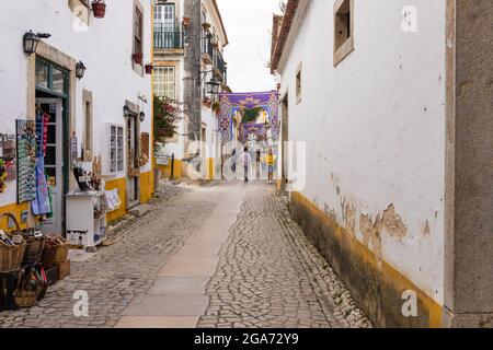 Obidos, Portugal - 30. Juni 2021: Malerische Straße mit touristischen Geschäften in der mittelalterlichen Stadt Obidos Stockfoto