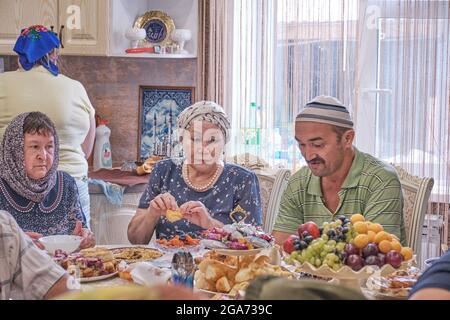 Die Bewohner des sibirischen Dorfes feiern den muslimischen Feiertag Kurban Bayram an ihrem Heimattisch. Dorfbewohner reden und essen. Eid al-Adha Stockfoto