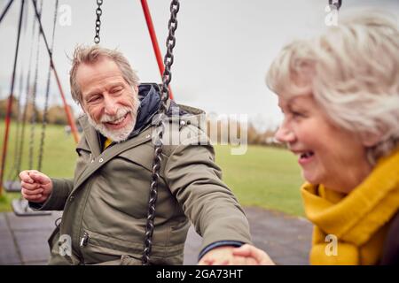 Ältere Paare, Die Spaß Beim Spielen Auf Schaukeln Im Park Playground Haben Stockfoto