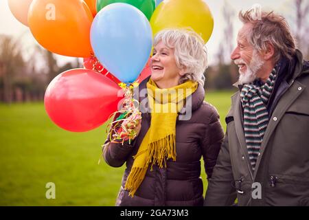 Liebende Senioren Halten Ballons Genießen Herbst Oder Winter Spaziergang Durch Park Zusammen Stockfoto