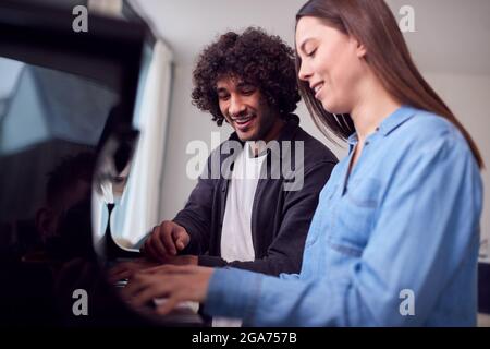 Junge Frau, Die Am Klavier Sitzt Und Unterricht Vom Männlichen Lehrer Hat Stockfoto