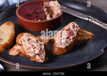 Zarte Hähnchenpastete mit pürierten Preiselbeeren auf gerösteten Baguette-Scheiben verteilen. Landestisches Essen. Stockfoto