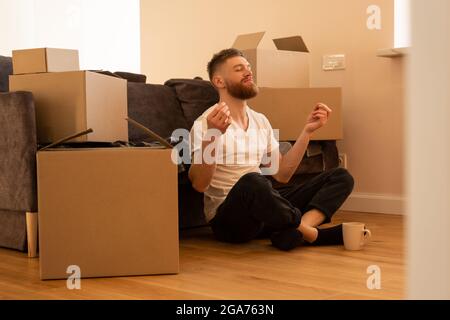 Entspannender junger Mann, der auf dem Boden sitzt und meditiert Stockfoto
