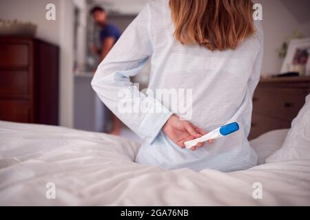 Nahaufnahme Einer Frau, Die Einen Schlafanzug Trägt Und Einen Positiven Schwangerschaftstest Hinter Dem Rücken Im Schlafzimmer Führt Stockfoto