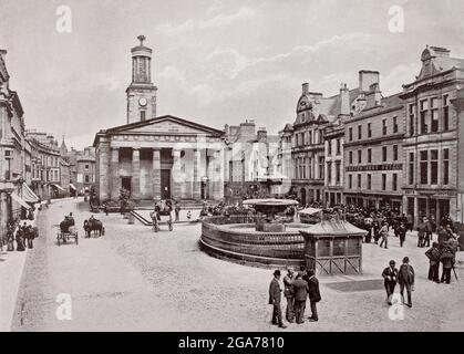 Eine Ansicht der High Street aus dem späten 19. Jahrhundert in Elgin, in Moray, Schottland, einer Stadt, die im 12. Jahrhundert von König David I. von Schottland als königliche Burg gegründet wurde. Am oberen Ende der Straße befindet sich die St. Giles' Church, eine Kirche von Schottland, die sich im Zentrum der Stadt befindet. Die Kirche wurde zwischen 1825 und 1828 erbaut und vom Architekten Archibald Simpson im neoklassischen Stil entworfen. Stockfoto