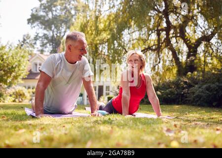 Senioren Zu Hause Im Garten Tragen Fitnesskleidung Und Genießen Yoga-Kurs Im Freien Stockfoto