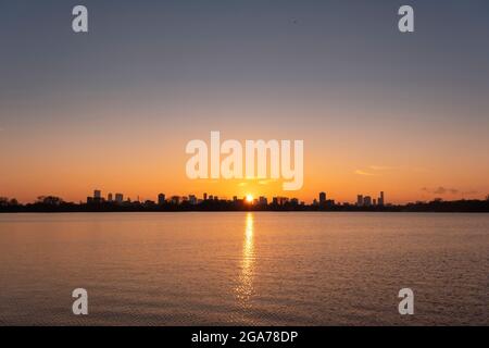 Sonnenuntergang über der Skyline von Rotterdam vom Kralingse Plas (Kralingen-See) aus gesehen, mit farbenprächtigem Himmel, der sich im stillen Wasser des Sees spiegelt Stockfoto