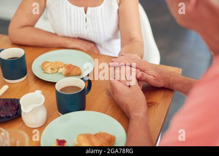 Nahaufnahme Eines Älteren Mannes, Der Eine Frau Tröstet, Die Unter Depression Leidet, Am Frühstückstisch Zu Hause Stockfoto