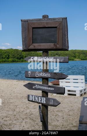 Leeres schwarzes Brett am weißen Sandstrand mit warmem Sonnenlicht in den niederlanden Stockfoto