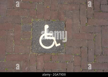 Logos für Behinderte auf dem Parkplatz. Handicap-Parkplatz Schild auf Ziegelsteinen Stockfoto