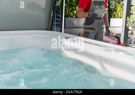 Kaukasischer Whirlpool-Techniker, der Wohngarten SPA-Service durchführt. Stockfoto