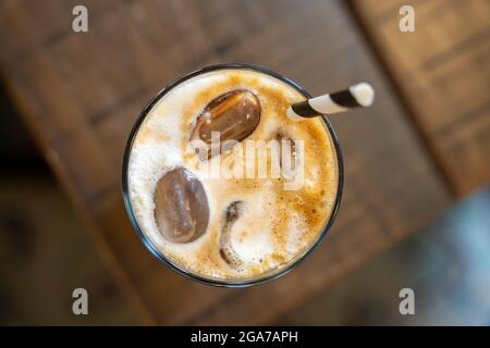 Von oben nach unten Blick auf einen Eislattenkaffee mit einem Stroh auf einem Holztisch, horizontal Stockfoto