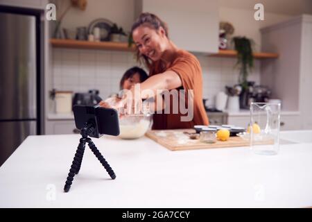 Asiatische Mutter Und Tochter Backen Cupcakes In Der Küche Zu Hause, Während Auf Vlogging Auf Handy Stockfoto