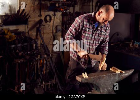 Schmied Hackt Holz Für Das Kinnieren Auf Dem Amboss Bis Zur Leichten Schmiede Stockfoto