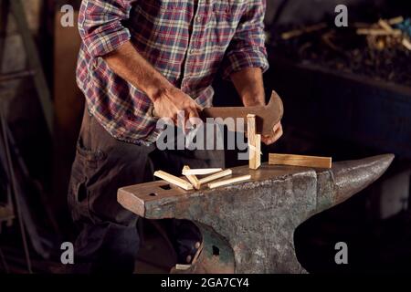 Nahaufnahme Des Schmieds, Der Holz Hackt, Für Das Kinnieren Auf Dem Amboss Bis Zur Leichten Schmiede Stockfoto