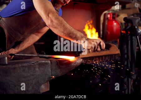 Nahaufnahme Eines Schmieds Mit Drahtbürste Auf Metallarbeiten, Die Auf Anvil Mit Sparks Ruhen Stockfoto