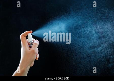 Nahaufnahme der Verwendung von antibakteriellem Handspray auf schwarzem Hintergrund. Stockfoto