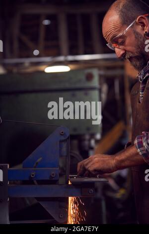 Schmied Formt Metallarbeiten Auf Belt Sander Mit Sparks Stockfoto