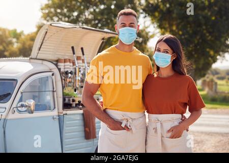 Porträt Eines Paares Mit Gesichtsmasken, Das Neben Van Einen Unabhängigen, Mobilen Coffee Shop Führt Stockfoto