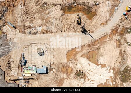 Neue Baustelle mit schweren Baumaschinen und Materialien. Luftaufnahme von oben. Stockfoto