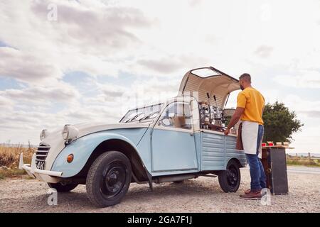 Mann, Der Einen Unabhängigen, Mobilen Coffee Shop Betreibt, Der Getränke Vorbereitet, Steht Im Freien Neben Van Stockfoto