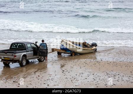 Trevaunance Cove, Großbritannien, 29. Juli 2021,EIN Mann kehrt in einem kleinen Holzboot an Land zurück, das er dann auf einen Anhänger am Strand verladen hat. Es gab Wellen in Trevaunance Cove vor dem Sturm Evert in St. Agnes, Cornwall. Der vierte genannte Sommersturm wird über Nacht für unSaison starke Winde und starken Regen sorgen.Quelle: Keith Larby/Alamy Live News Stockfoto