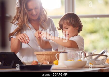 Mutter Und Sohn Im Pyjama Pfannkuchen In Der Küche Zu Hause Nach Rezept Auf Digital Tablet Stockfoto