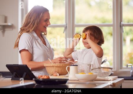 Mutter Und Sohn Im Pyjama Pfannkuchen In Der Küche Zu Hause Nach Rezept Auf Digital Tablet Stockfoto
