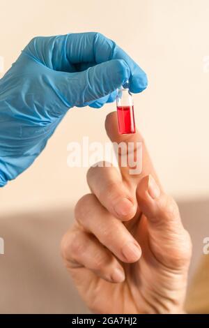 Die Hand einer Krankenschwester reicht einer älteren Frau eine Ampulle Medizin aus Stockfoto