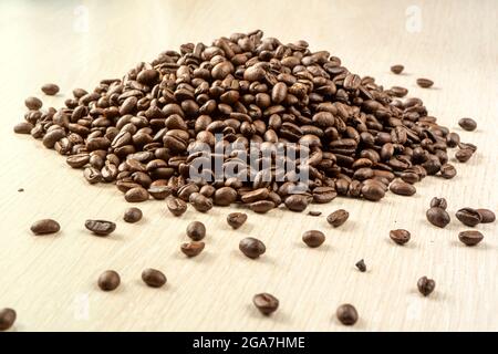Geröstete braune Kaffeebohnen auf weißem Tisch mit viel verstreut. Nahaufnahme Stockfoto