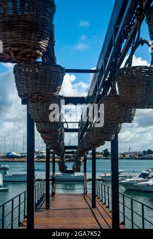 Fischerboote vom hölzernen Pier aus gesehen, der mit hängenden Korbkörben geschmückt ist - Partimao, Portugal, Vertikal Stockfoto