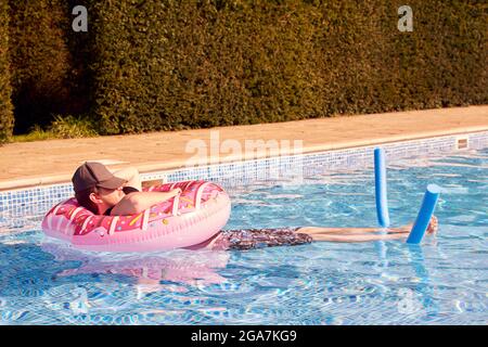 Junger Mann, Der Sich Im Sommerurlaub Entspannt, Schwimmt Im Swimmingpool Im Aufblasbaren Ring Stockfoto
