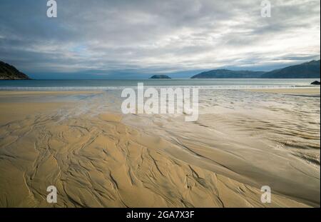 Muster und Reflexionen, die durch die Ebbe an einem Strand in Estaca de Bares in Galicien entstehen Stockfoto