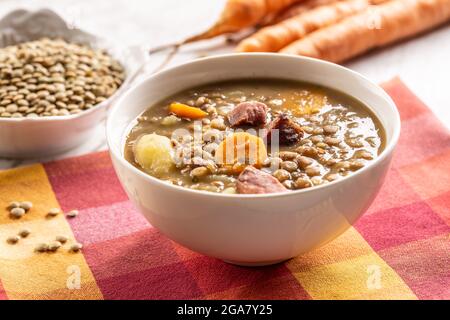Linsensuppe mit geräuchertem Schweinehals, Karotten und Kartoffeln. Traditionelle slowakische, tschechische oder osteuropäische Küche. Stockfoto