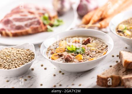 Linsensuppe mit geräuchertem Schweinehals, Karotten, Kartoffeln und Koriander. Traditionelle slowakische, tschechische oder osteuropäische Küche. Stockfoto