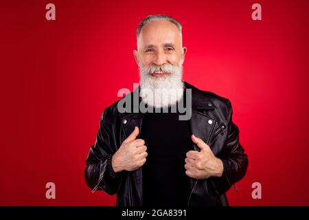 Portrait von attraktiven fröhlich modischen grauhaarigen Mann trägt coole Jacke isoliert über hellen roten Hintergrund Stockfoto