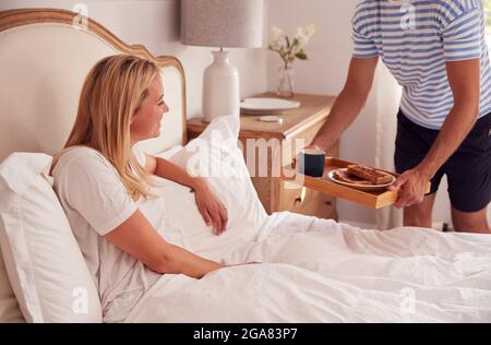 Ehemann Überraschend Frau Mit Frühstück Im Bett Zu Hause Stockfoto