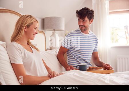 Ehemann Überraschend Frau Mit Frühstück Im Bett Zu Hause Stockfoto