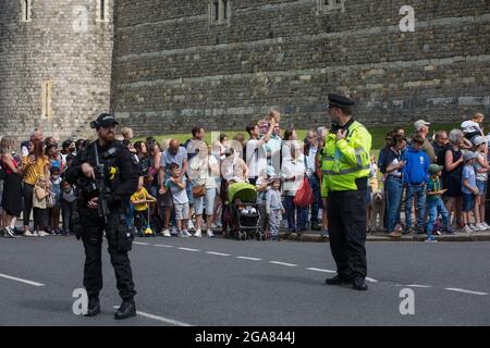 Windsor, Großbritannien. Juli 2021. Polizeibeamte aus dem Thames Valley überwachen Touristen und Anwohner, die nach der Wachablösung auf den Abflug der Alten Wache vom Schloss Windsor warten. Die Zeremonie, die auch als Guard Mounting bekannt ist, wurde am 22. Juli zum ersten Mal seit Beginn der Covid-19-Pandemie im März 2020 wieder aufgenommen. Kredit: Mark Kerrison/Alamy Live Nachrichten Stockfoto