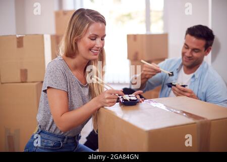 Pärchen Feiern Mit Takeaway-Sushi-Essen Auf Dem Boden Des Neuen Heims Am Umzugsfeiertag Stockfoto