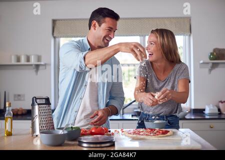 Paar In Der Küche Zu Hause Gemeinsam Käse Auf Hausgemachten Pizzas Verteilen Stockfoto
