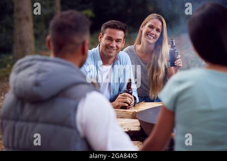 Gruppe Von Freunden Camping Sitzen Bei Bonfire In Fire Bowl Feiern Und Trinken Bier Zusammen Stockfoto