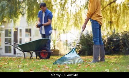 Reifes Asiatisches Paar, Das Im Garten Zu Hause Arbeitet, Rakend Und Aufräumend Blätter In Barrow Stockfoto