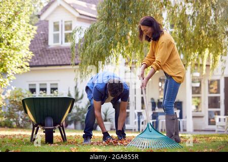 Reifes Asiatisches Paar, Das Im Garten Zu Hause Arbeitet, Rakend Und Aufräumend Blätter In Barrow Stockfoto