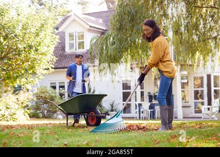 Reifer Asiatischer Mann Bringt Heiße Getränke Zur Frau Aufräumen Garten Mit Rake Stockfoto