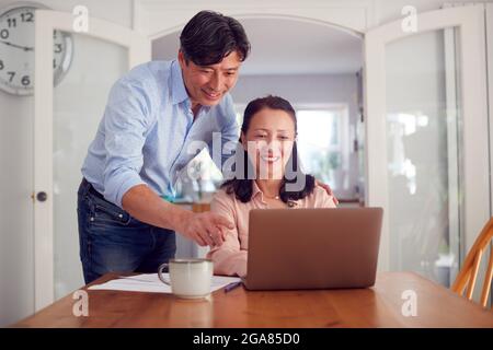 Reifes Asiatisches Paar Zu Hause Mit Laptop, Um Haushaltsrechnungen Und Finanzen Zu Organisieren Stockfoto